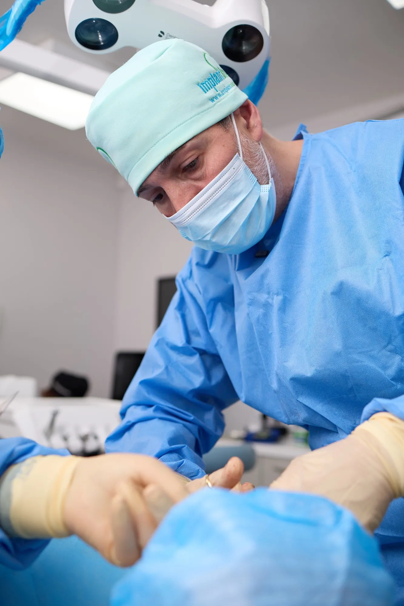 Dental implant surgery under the theatre light, Dr Brad Hawkins working with an assistant