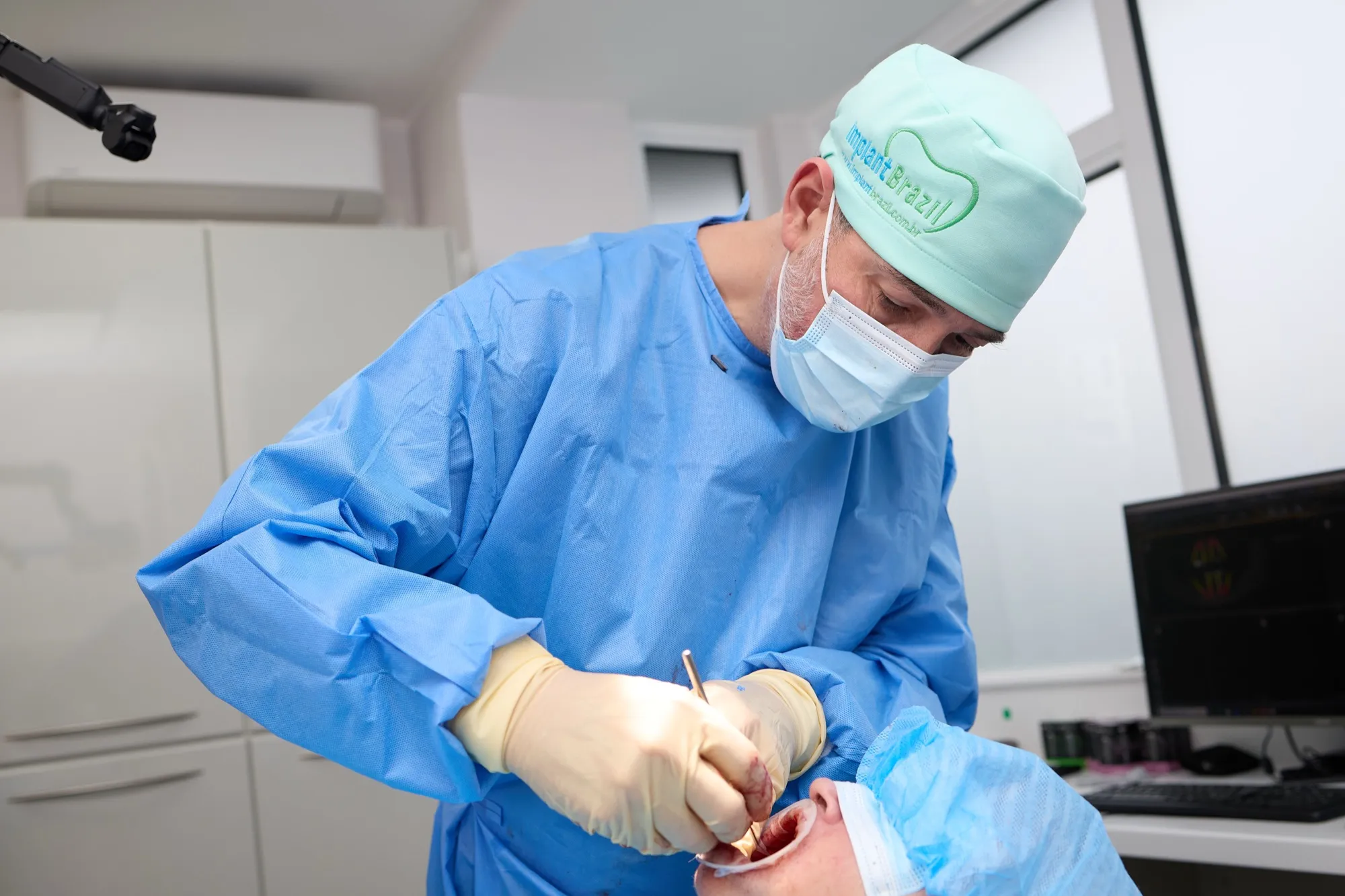 Dr Brad Hawkins in surgical gown and cap, placing dental implants during full-arch treatment
