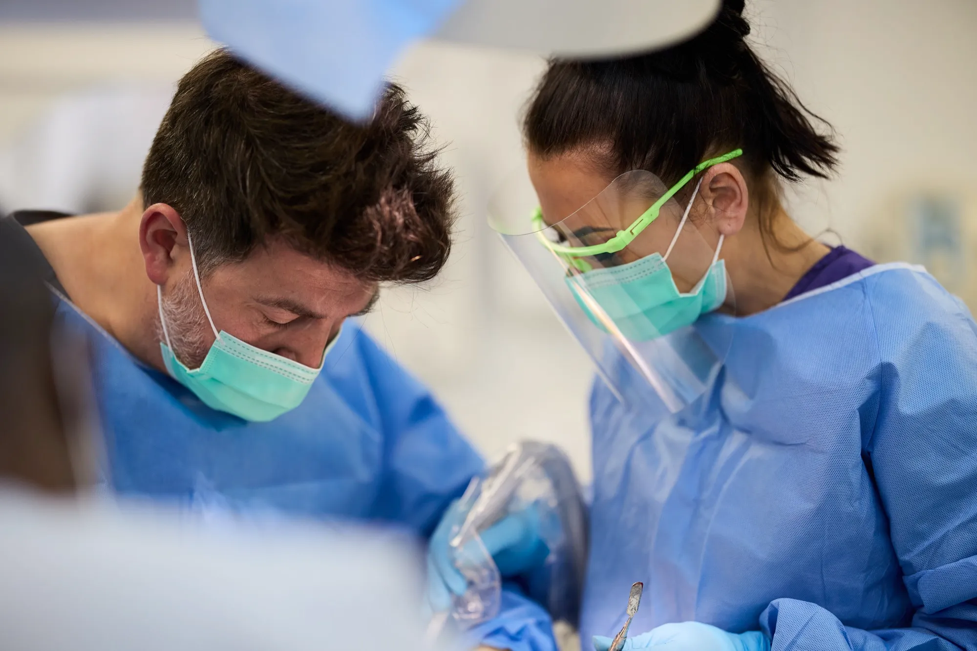 Dr Brad Hawkins and a nurse in surgical gowns and masks, working together during implant surgery