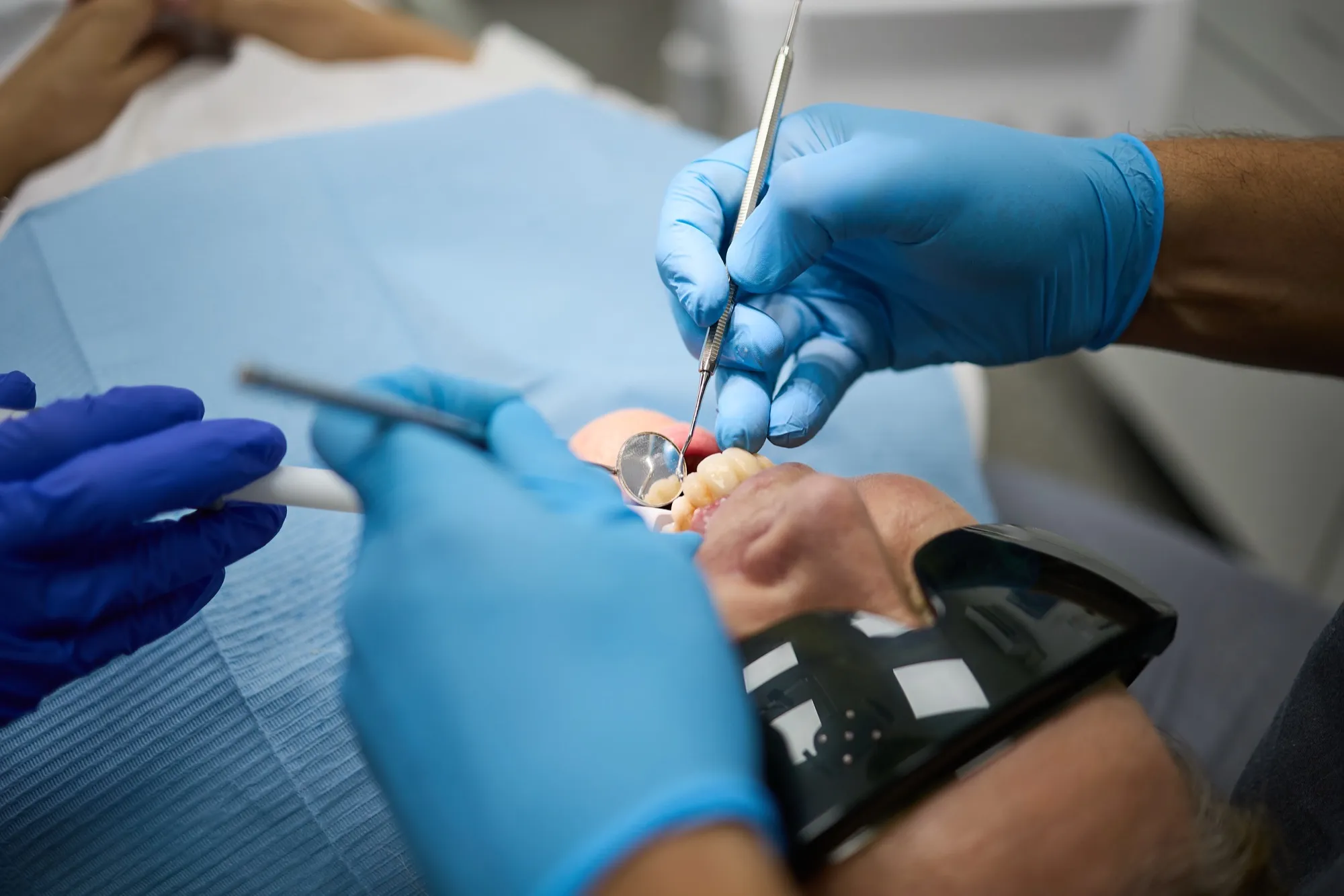 Gloved hands working over a model of the teeth alongside a tablet, planning implant treatment